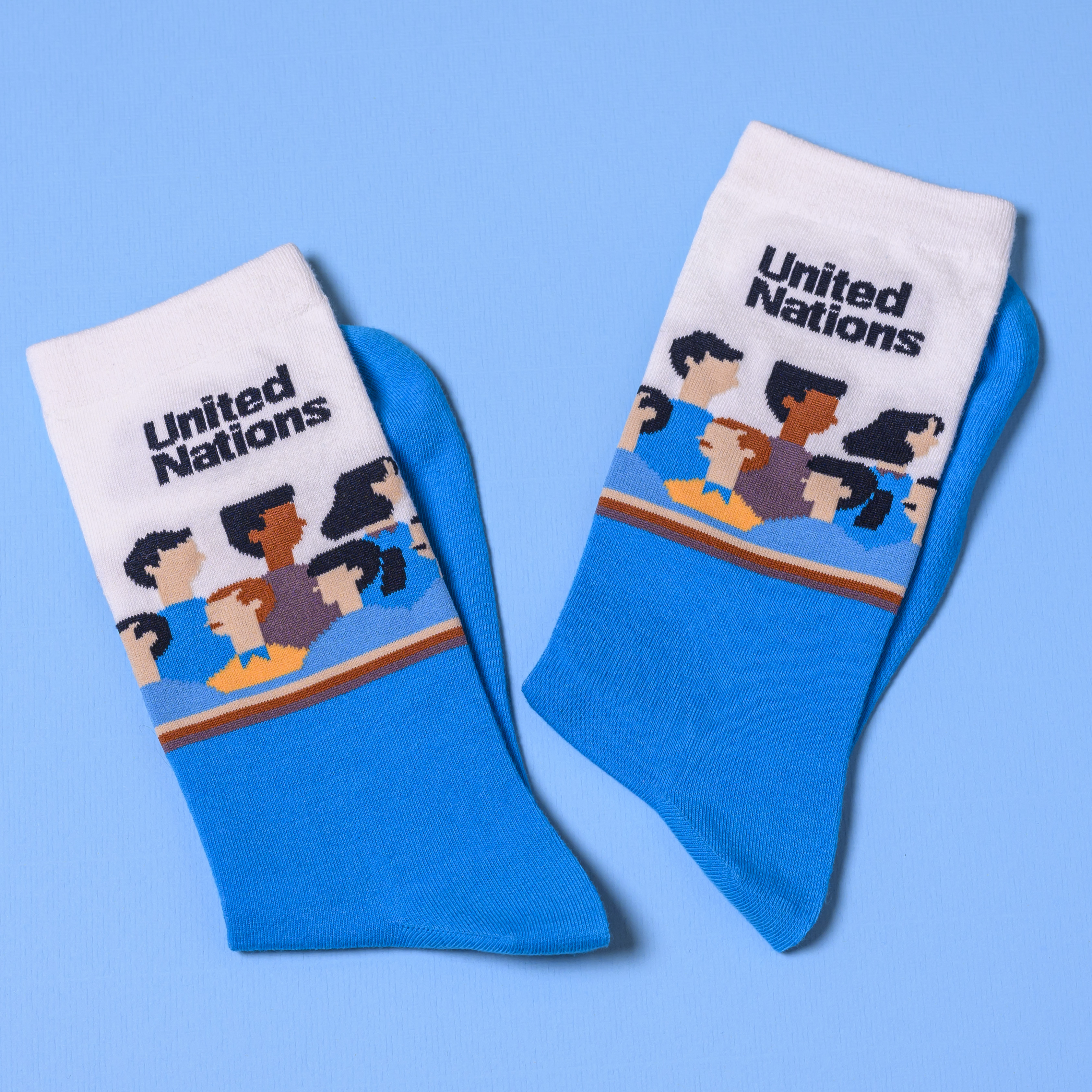A pair of blue and white United Nations themed crew socks featuring illustrated character graphics and custom branding.