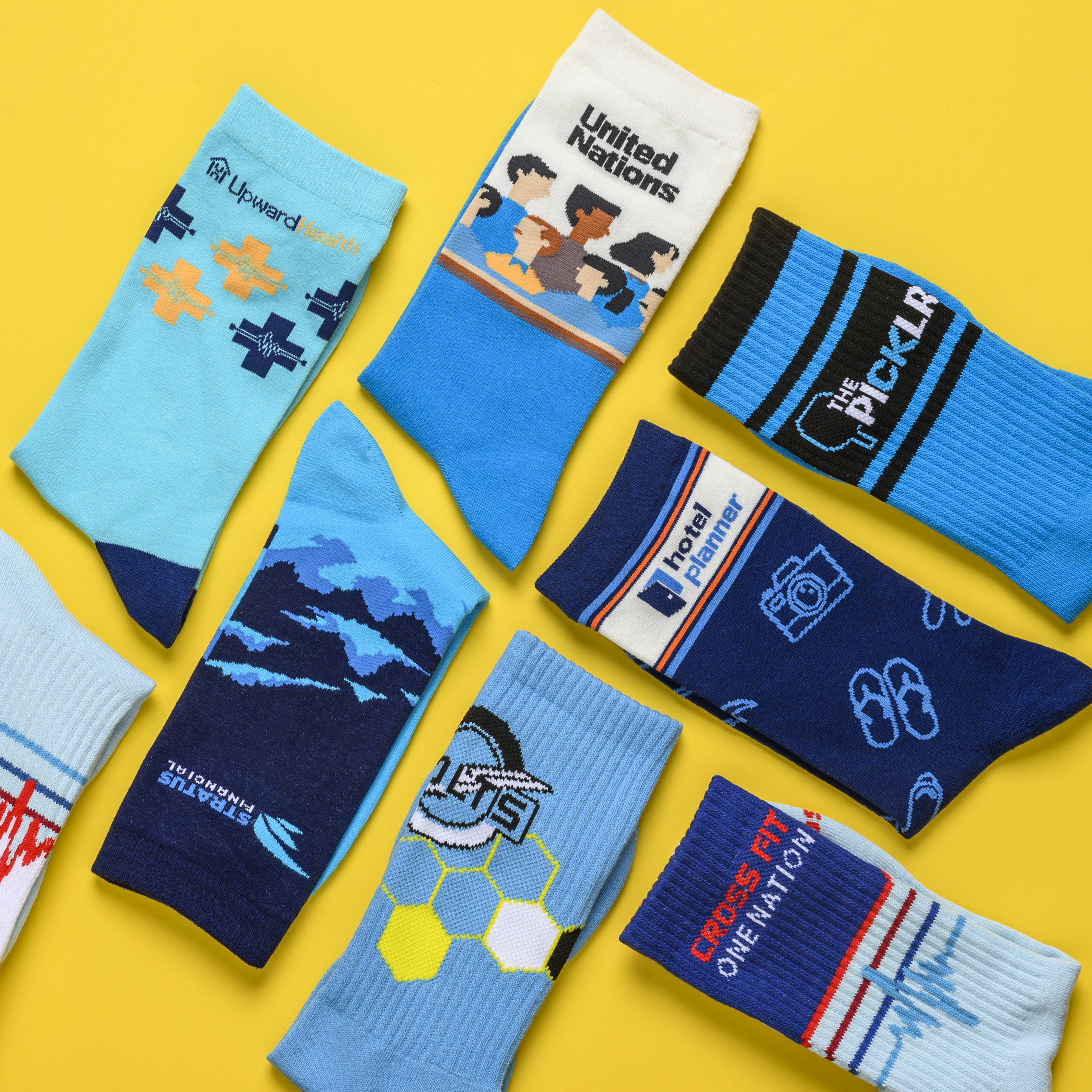 An overhead shot of multiple pairs of custom-branded blue socks scattered on a yellow background.