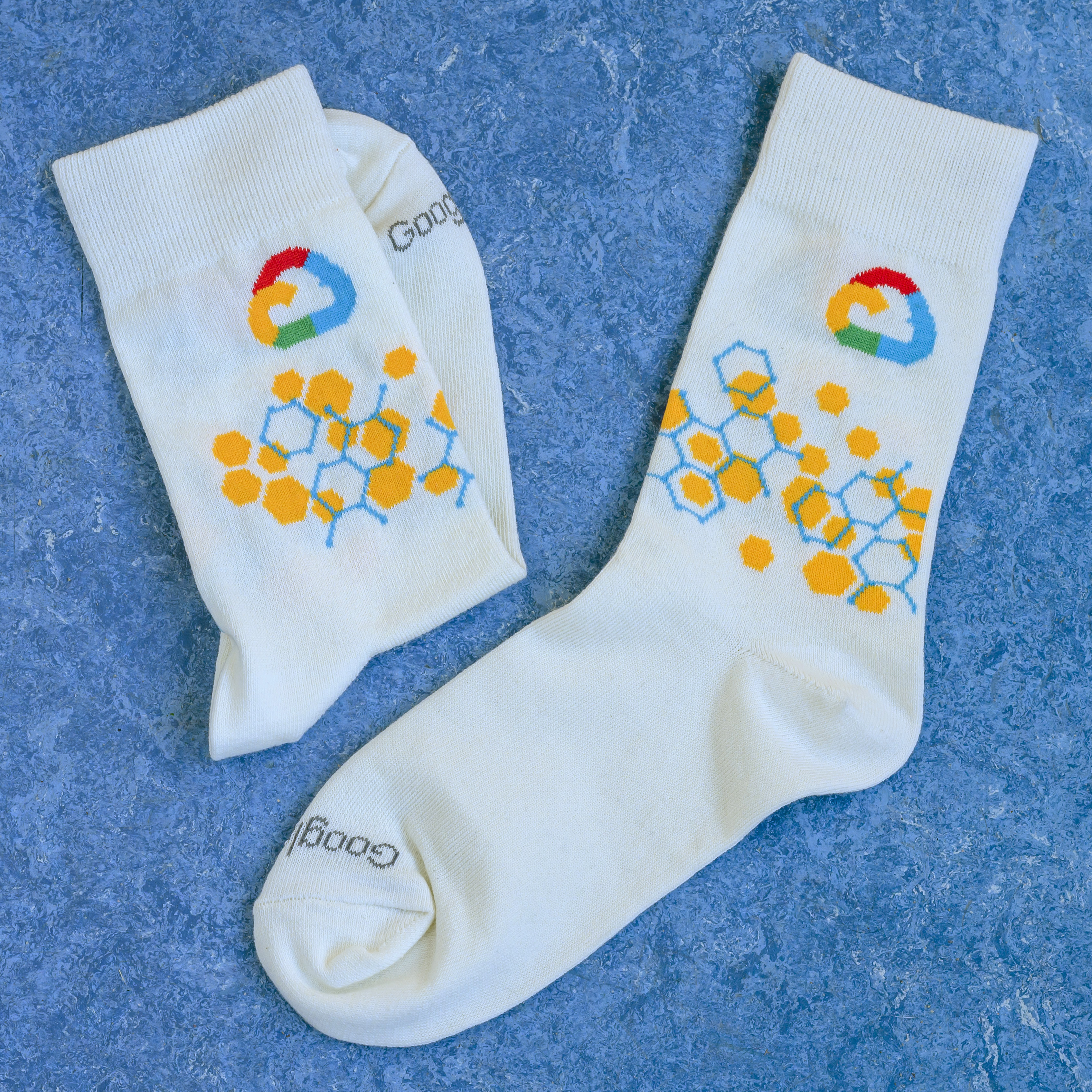 A pair of white socks with the Google Cloud logo and a yellow and blue hexagonal pattern.