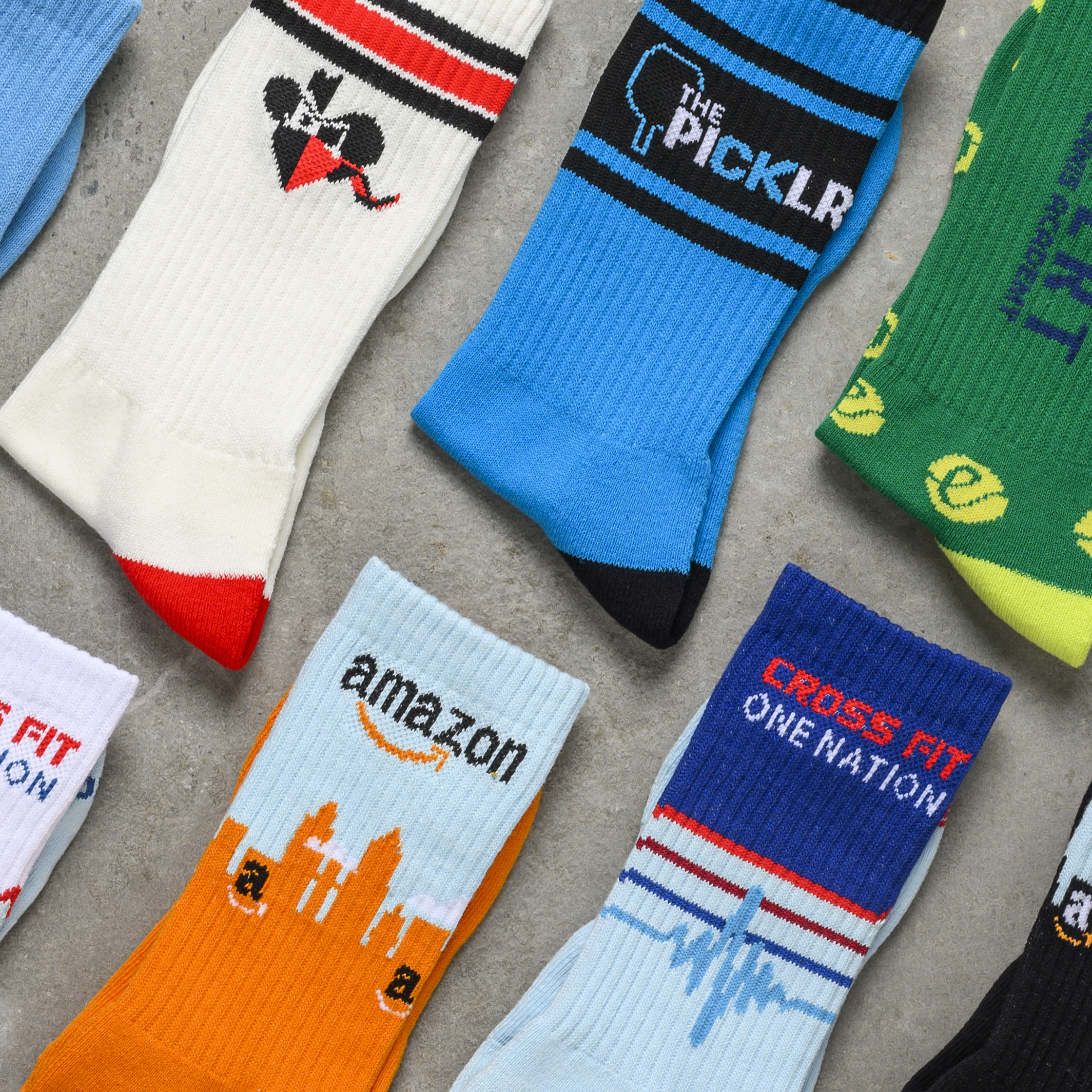 A collection of custom branded athletic socks featuring colorful logo designs and vibrant performance styles.