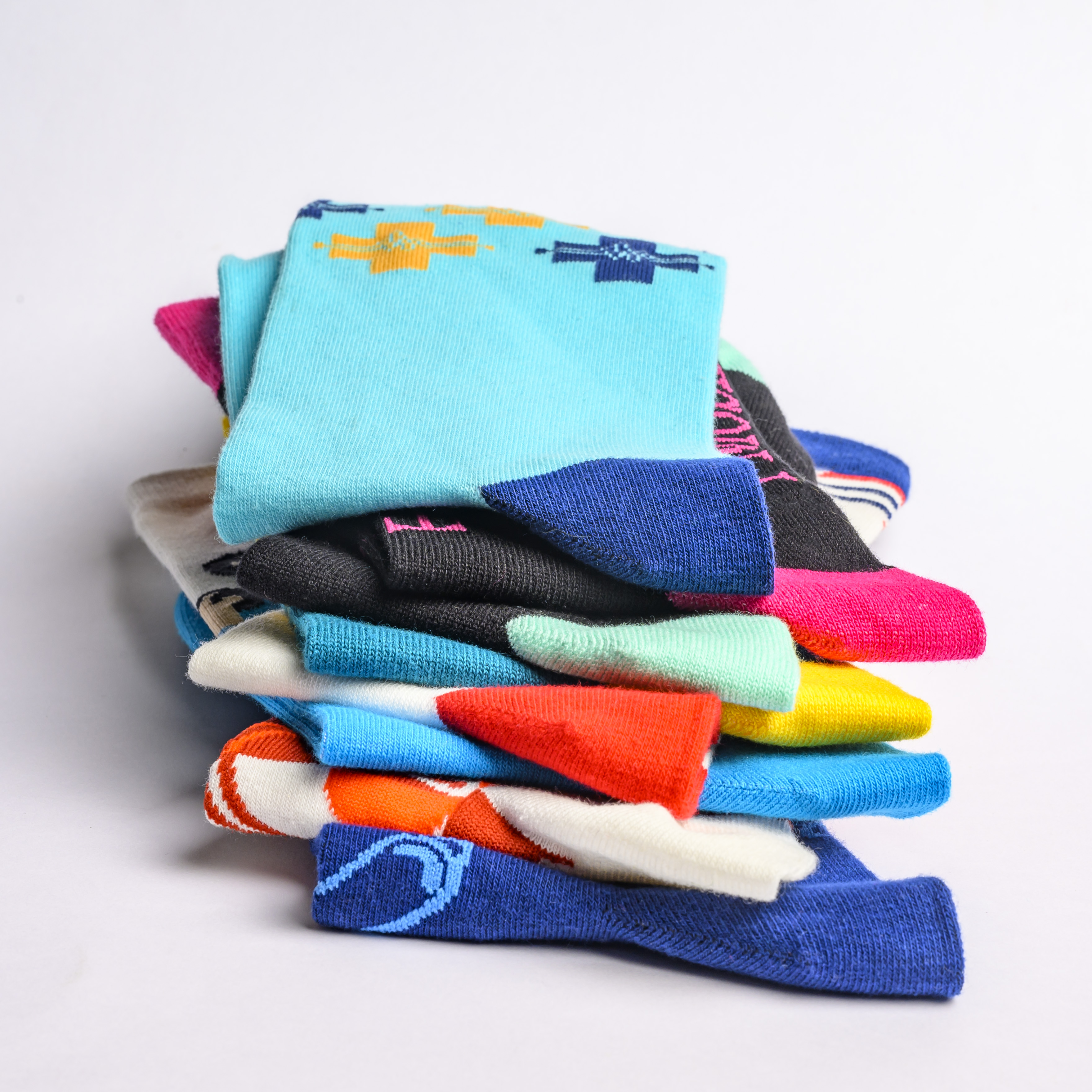 A stack of colorful custom crew socks showcasing various knit patterns and brand designs.