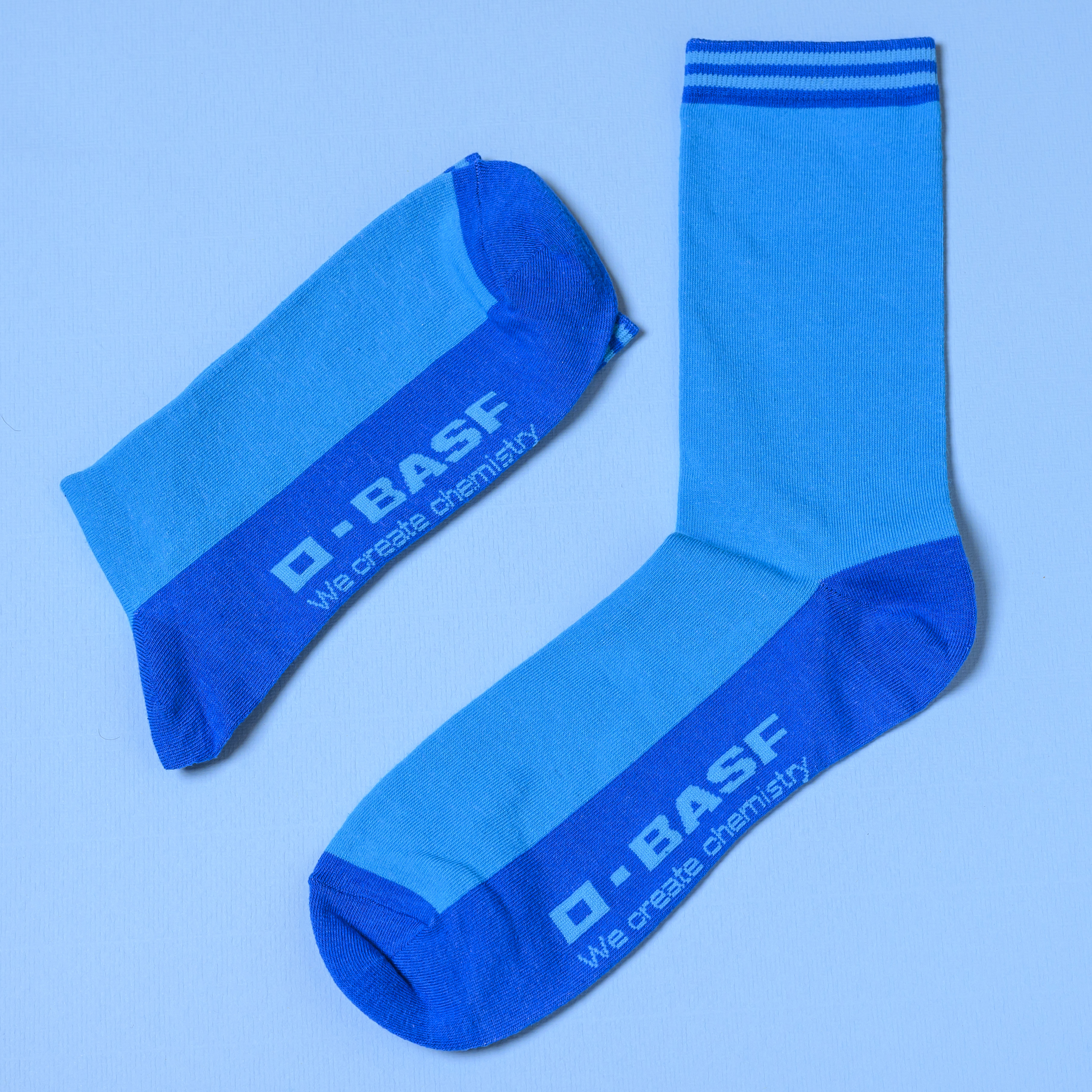 A pair of blue BASF branded crew socks with tonal pattern detailing and athletic knit construction.