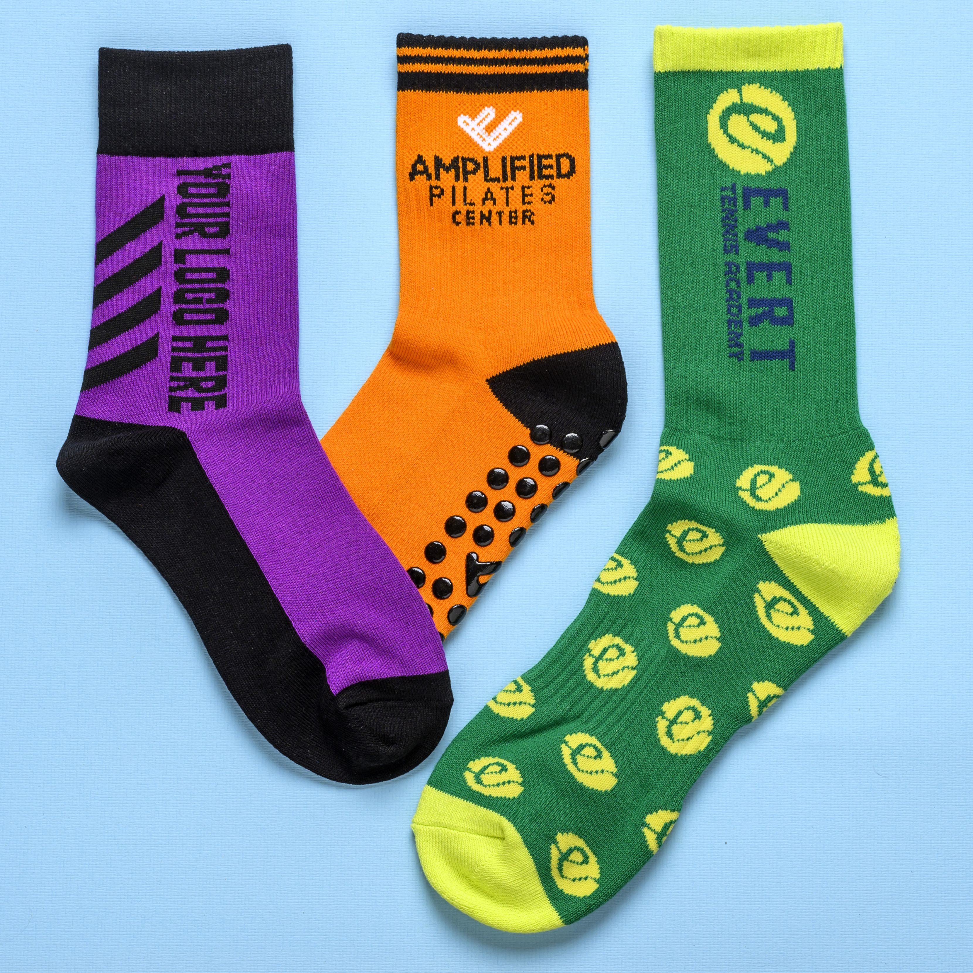 Three colorful athletic socks with different custom logos and designs on a blue background.