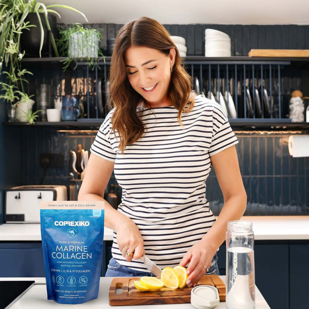 Woman slicing lemons in a kitchen with marine collagen product on counter.