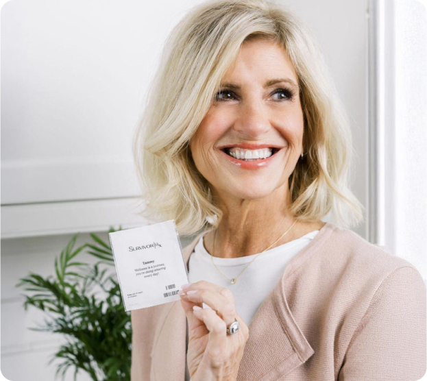 Woman smiling while holding a skincare product in a modern interior setting.
