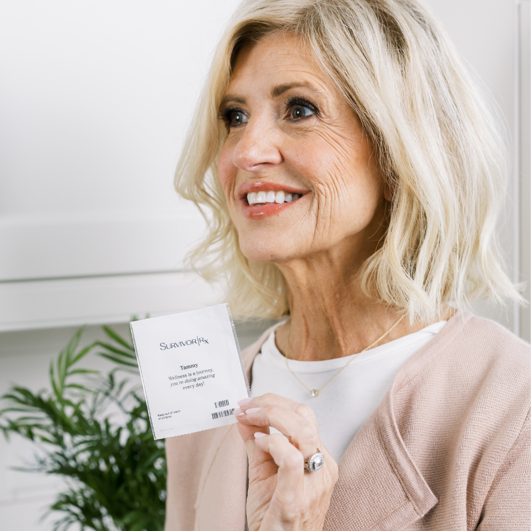 Smiling woman holding a small white packet near plants.