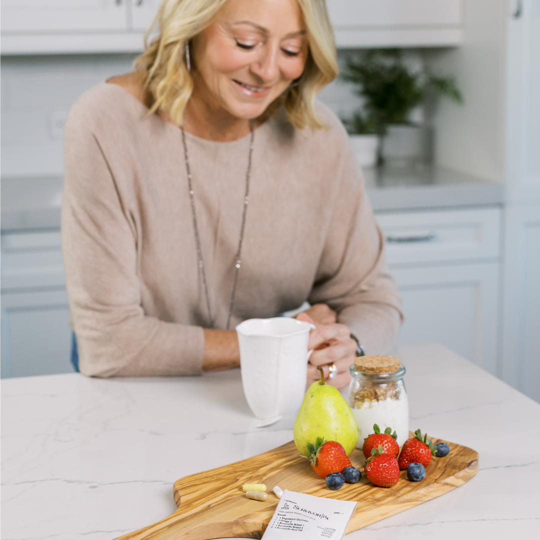 Woman in kitchen with fruit platter and cup, smiling.