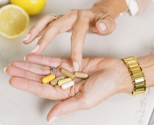 Hands holding various colored capsules with a lemon in the background.