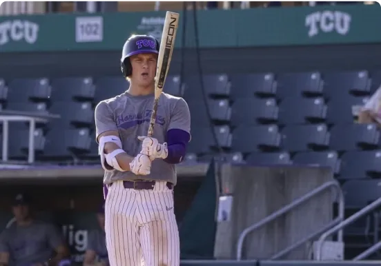 Baseball player in uniform holding a bat in a stadium.