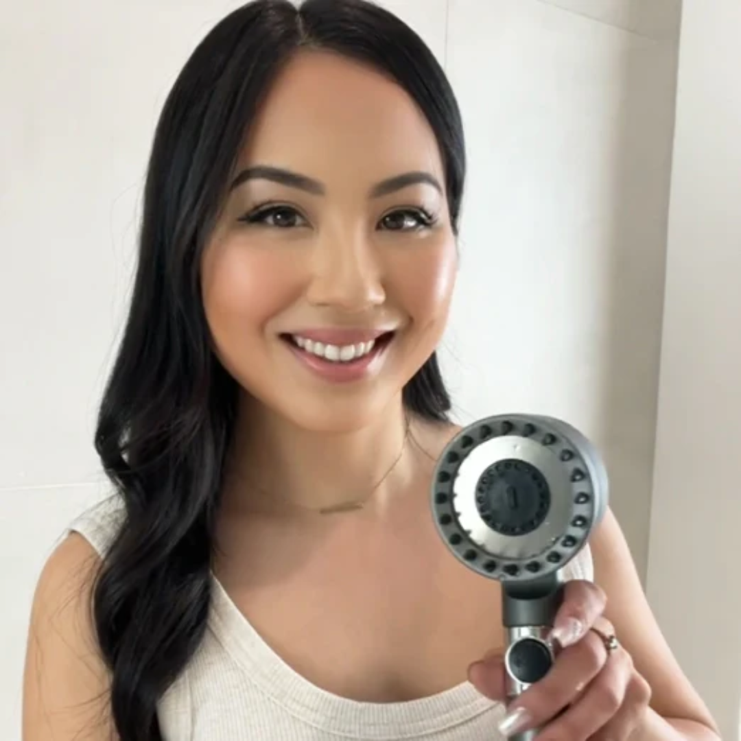Person smiling and holding a showerhead.