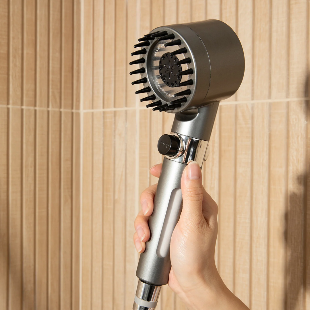 Hand holding a modern shower head against a wooden wall.