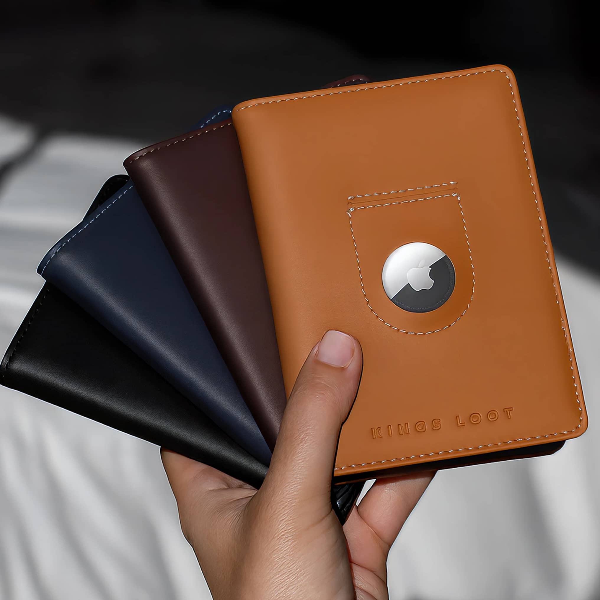 Person holding four leather wallets in different colors.