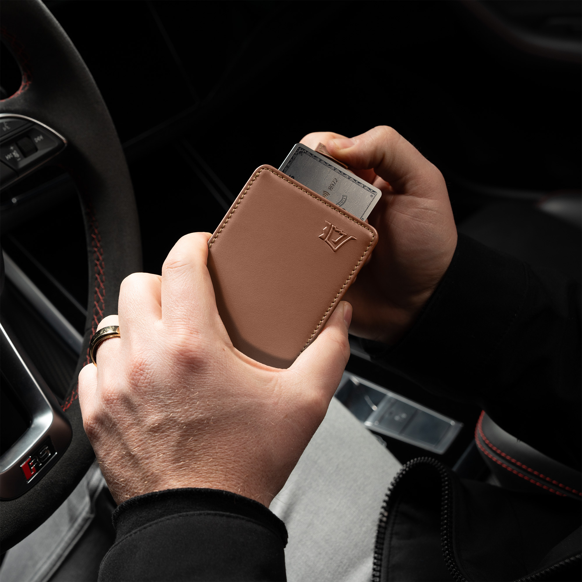 Person holding a brown wallet with cards in a car.