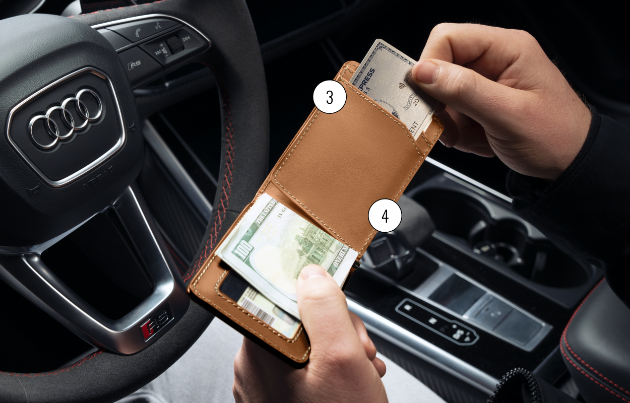 Person holding a wallet with cash and card inside a car.