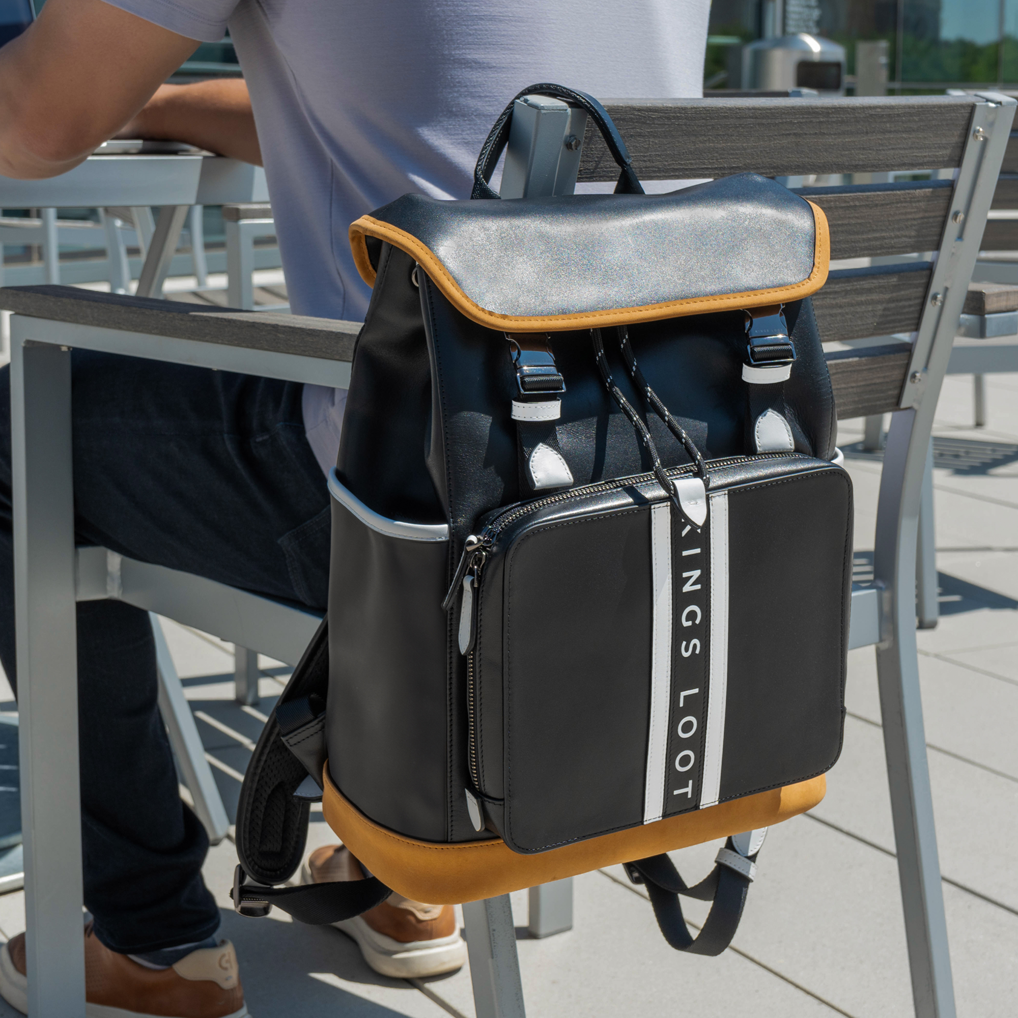 Black and tan backpack hanging on a chair outdoors.