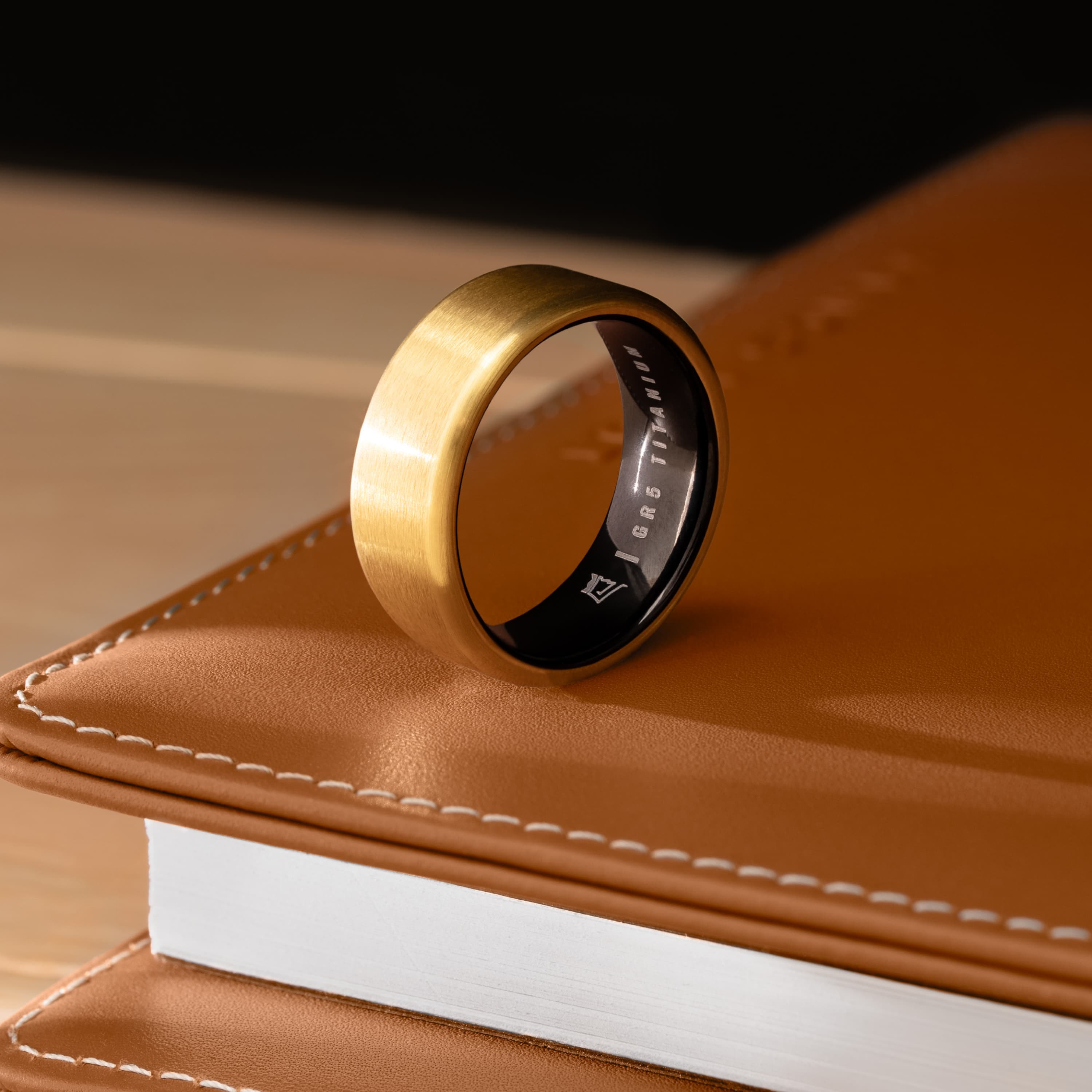 Gold ring with black interior on a leather book.