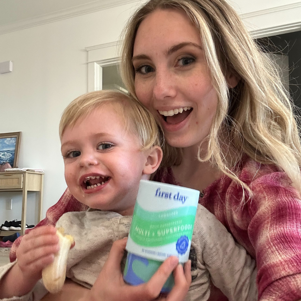 Woman and child smiling, holding a container and a snack.