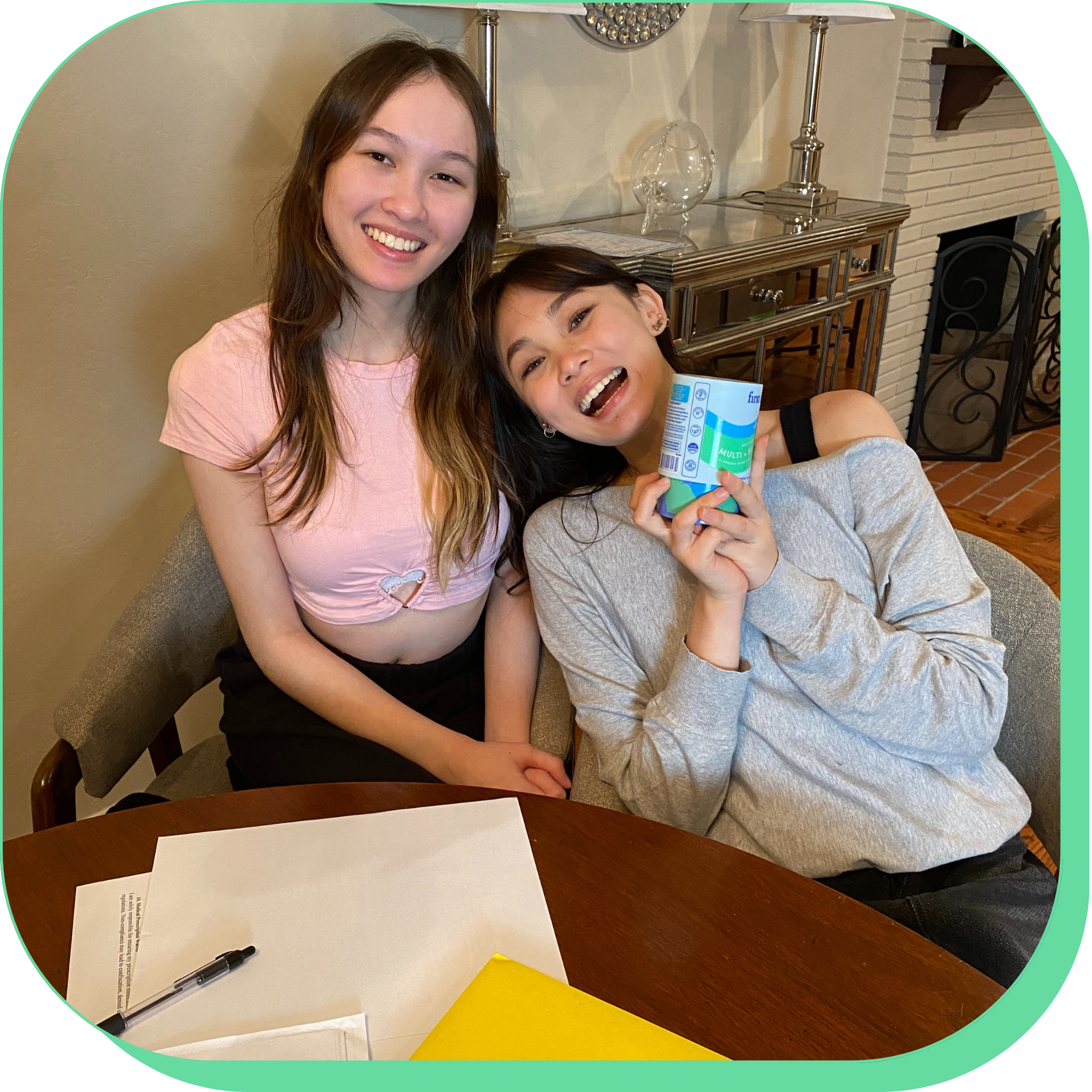 Two people smiling at a table, one holding a product.