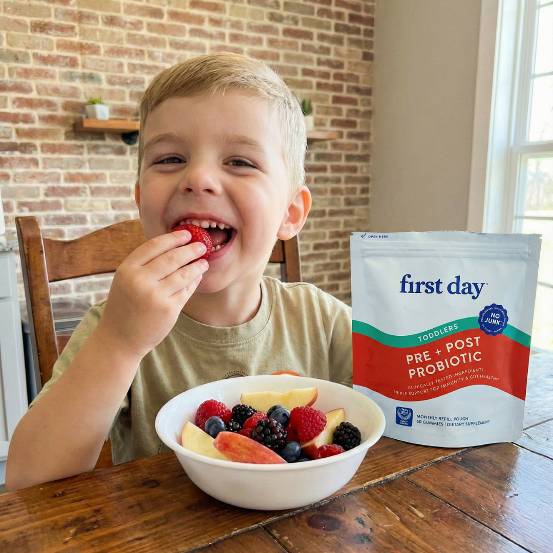 Child eating berries from a bowl with probiotic packet beside.