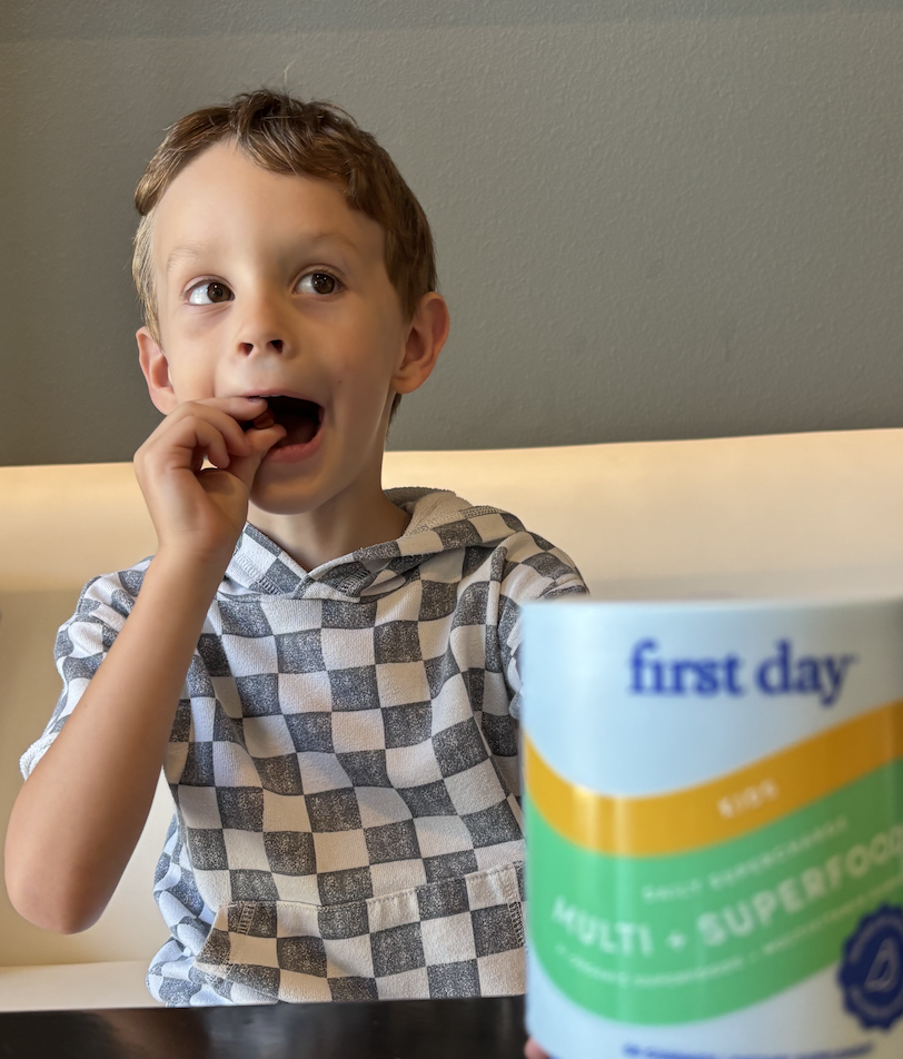 Child eating with a container labeled 'first day' in the foreground.