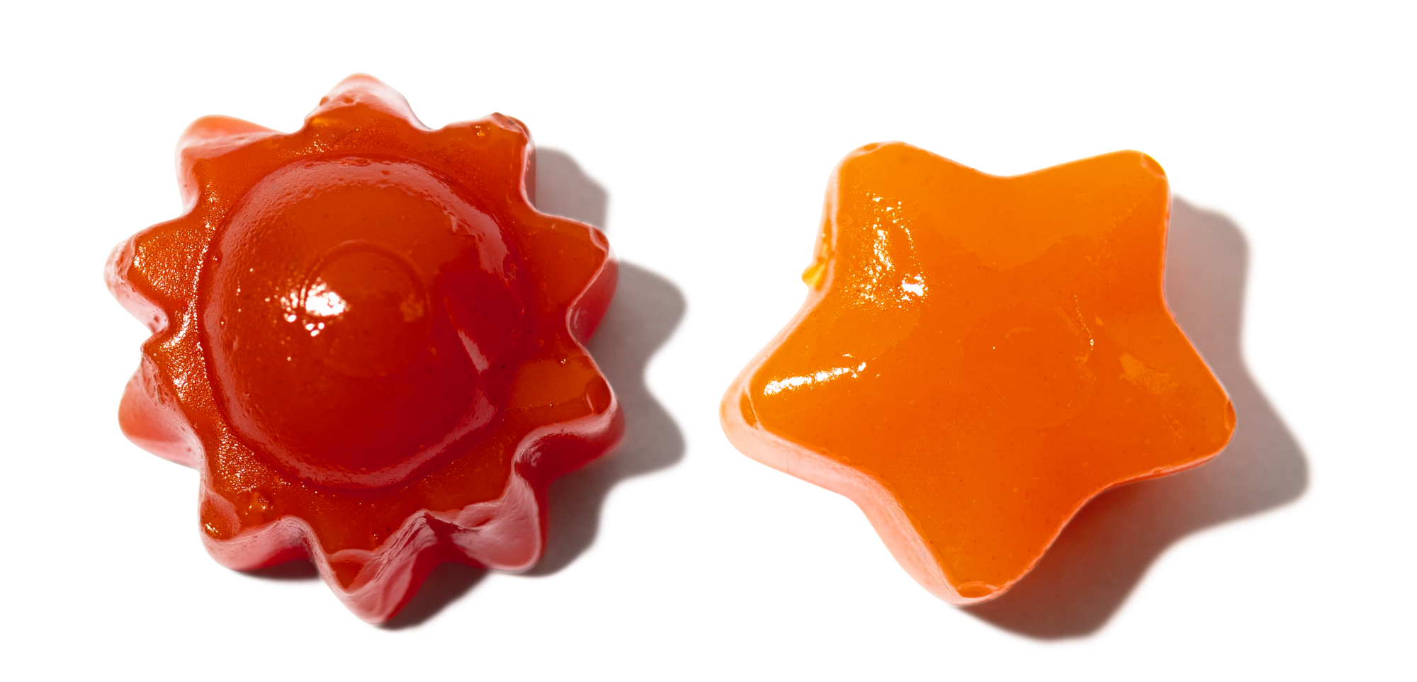 Two gummy candies, one sun-shaped and one star-shaped, on a black background.