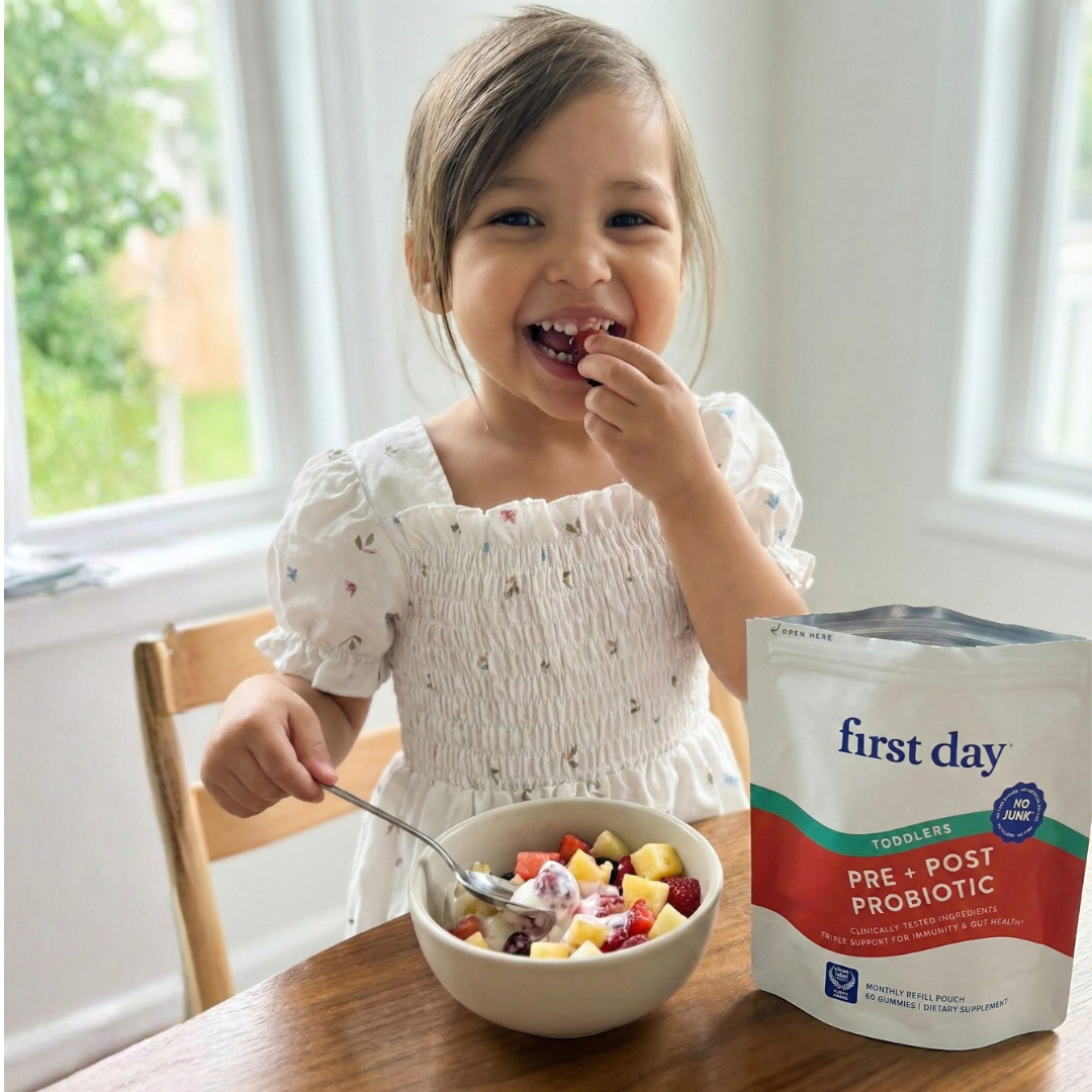 Child eating fruit salad next to a packet labeled 'first day' probiotics.