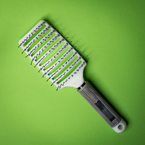 A vented hairbrush with a black handle on a green background.