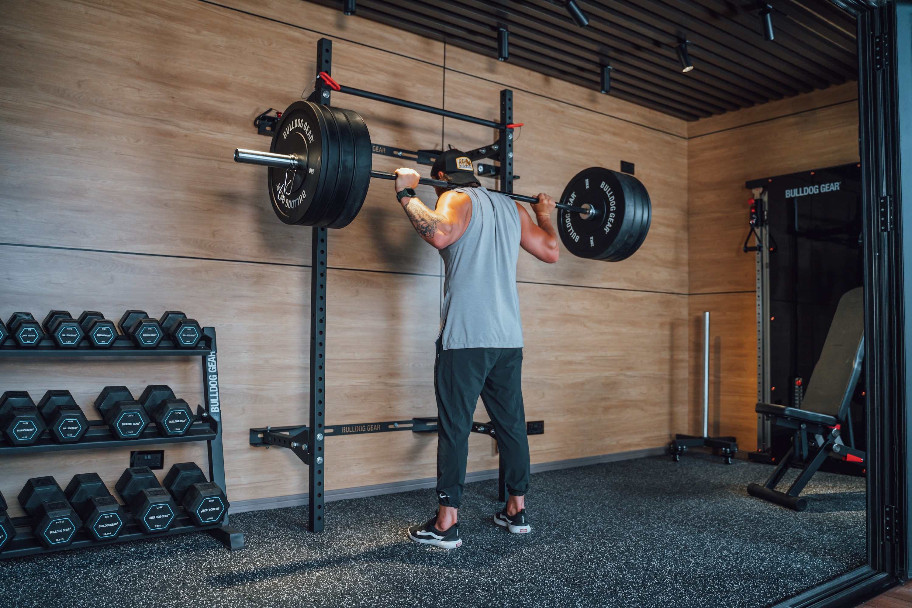 Person lifting weights in a gym with wooden walls and equipment.