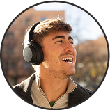 Person smiling while wearing headphones outdoors.