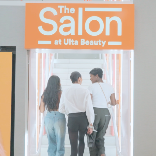 Three people walking up stairs under a Salon sign.