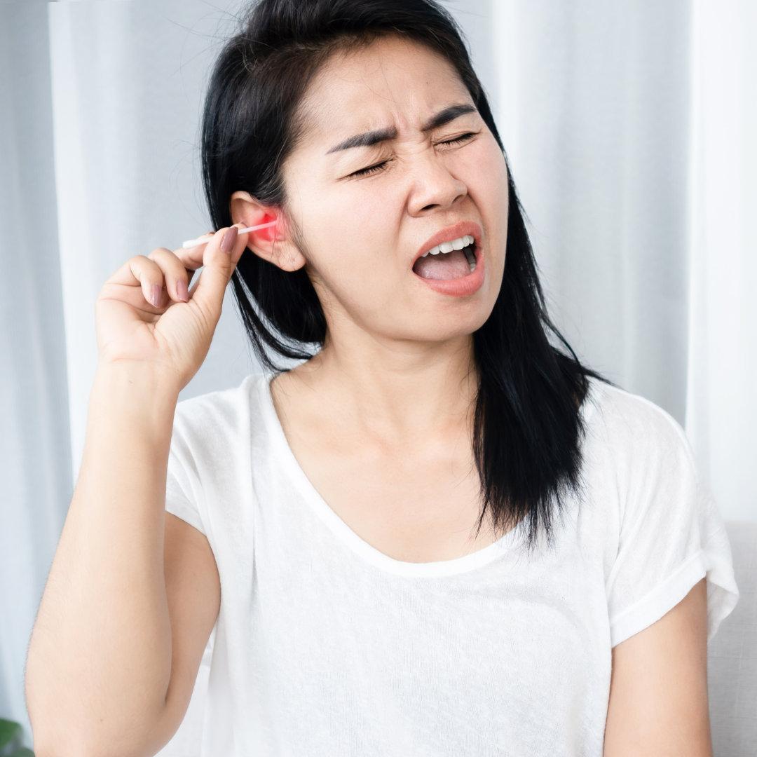 Person wincing while using a cotton swab in their ear.