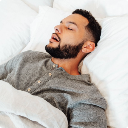 Person sleeping peacefully in bed with white sheets.