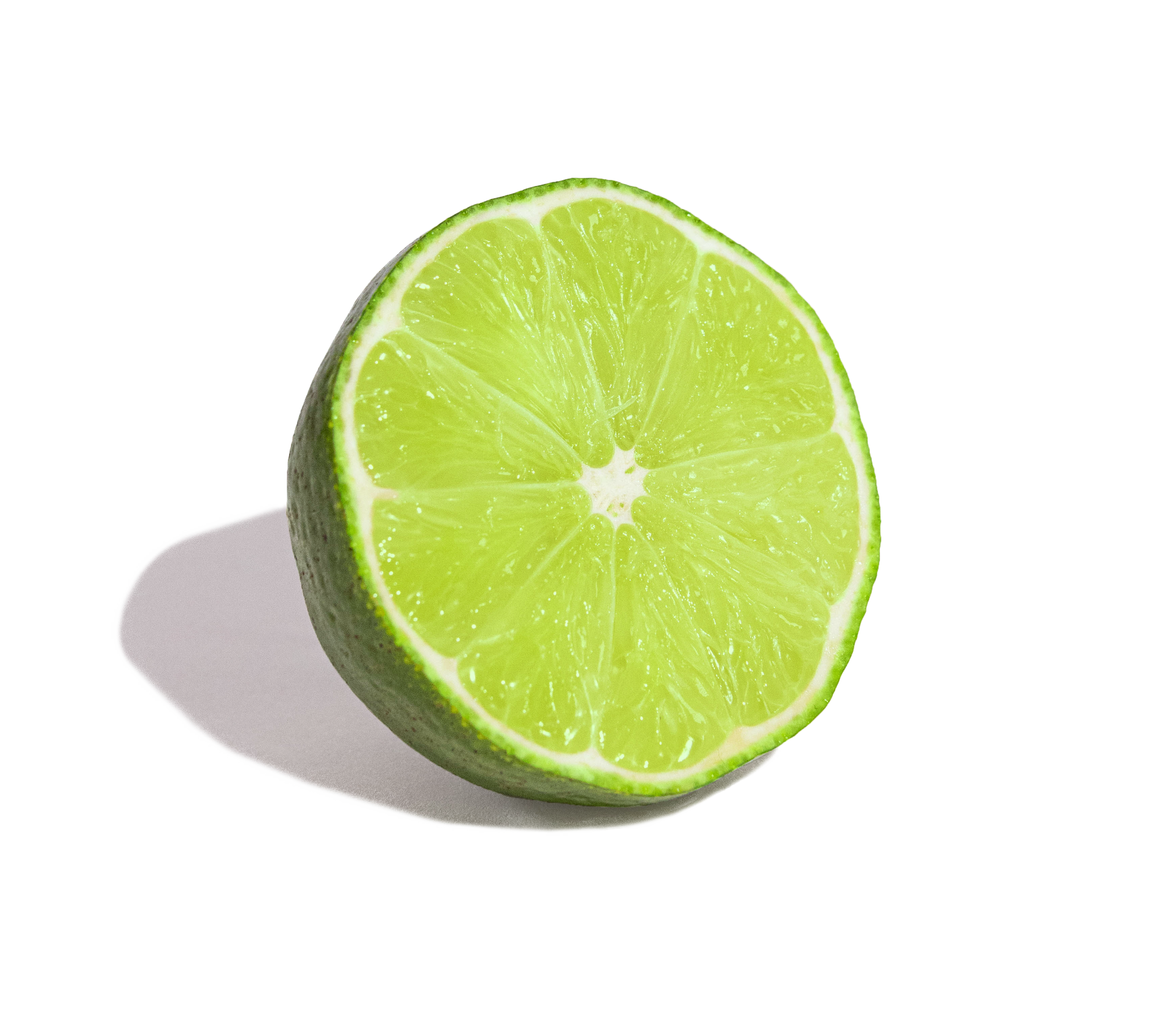 A sliced lime on a white surface with shadow.