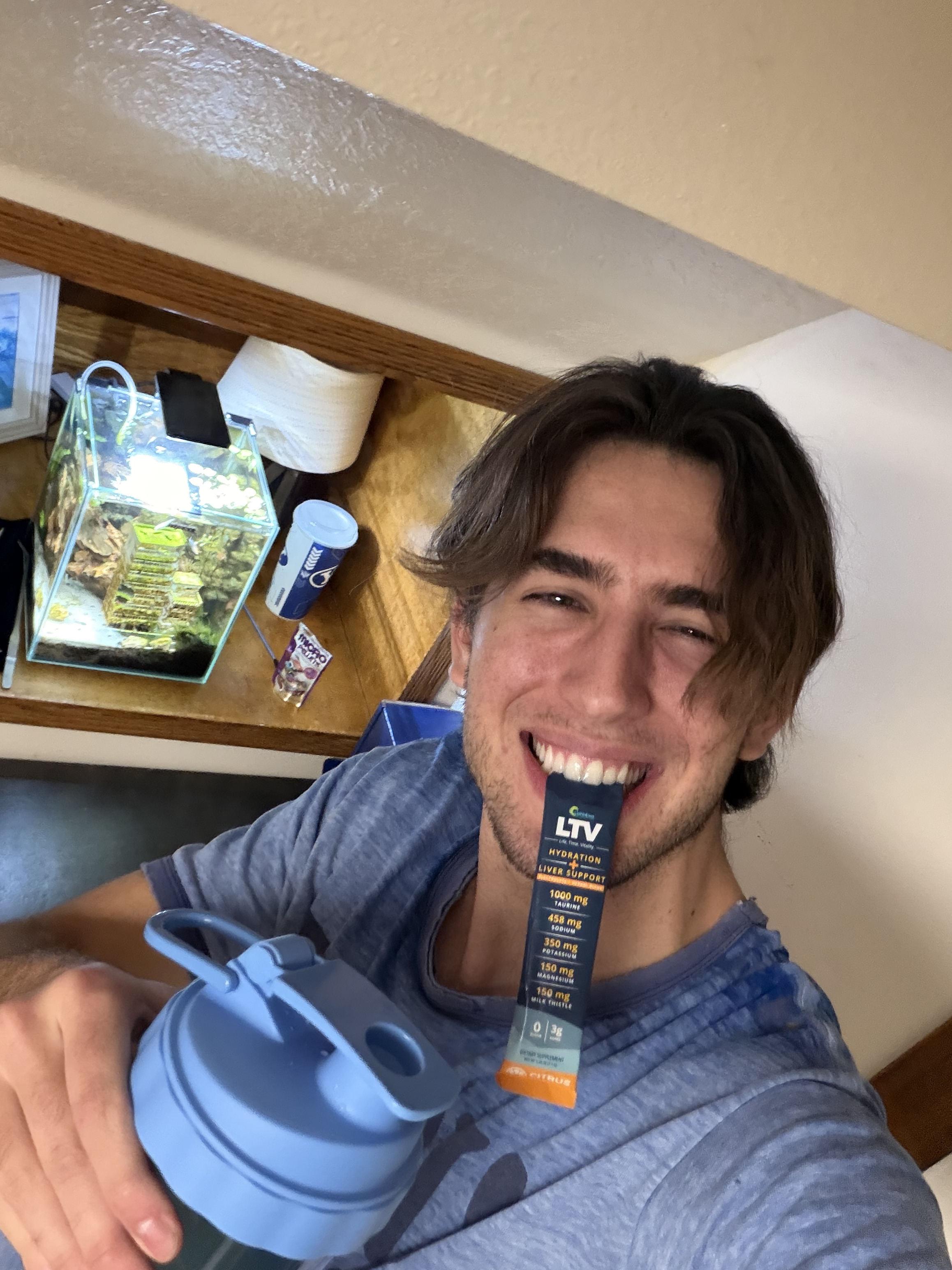 Potted green plant in a minimalist wooden stand against a beige curtain background.