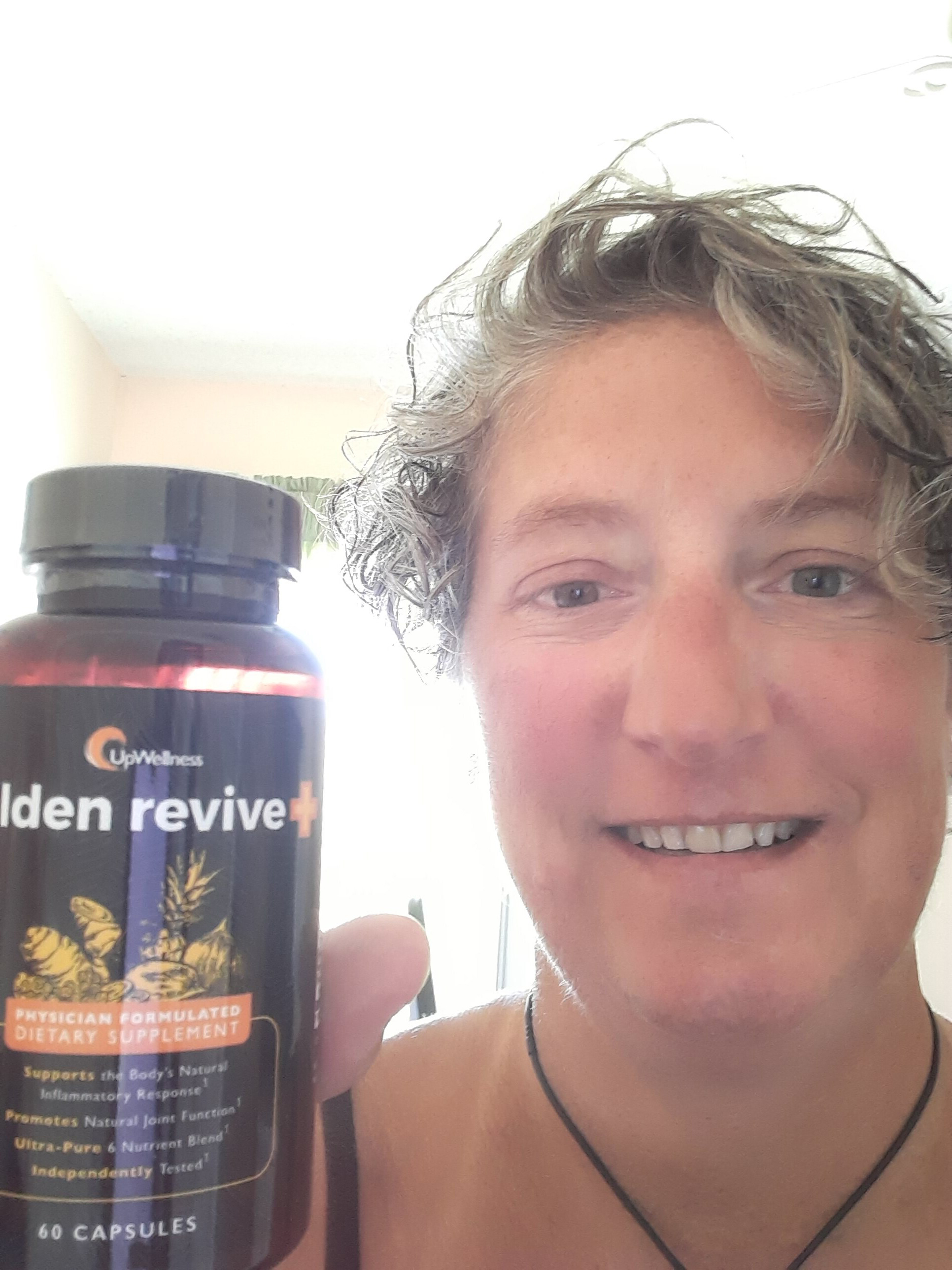 A smiling woman with glasses and long brown hair holds up a packet of LTV hydration supplement.