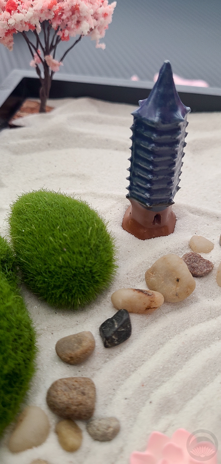 Miniature zen garden with rocks, moss, and a small tree.