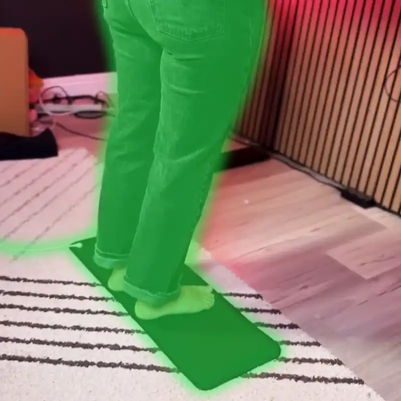 Person standing on a green mat in a room with striped rug.