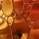 A close-up, abstract view of golden and amber-colored oil droplets of various sizes.