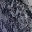 A close-up, angled view of a dark and jagged rock face.
