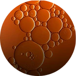 A circular, microscopic view of various sized amber-colored bubbles.