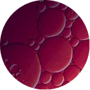 A circular, abstract close-up of reddish-purple oil droplets of various sizes.