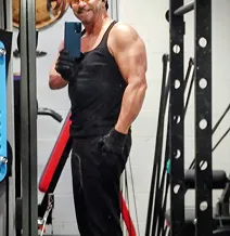 Person taking a mirror selfie in a gym, wearing black workout clothes.