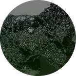 A circular close-up of a dark, coarse, and glittery textured substance.