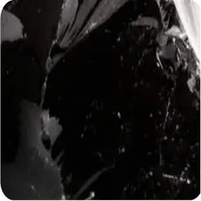 A close-up of a shiny, black, fractured rock-like substance, possibly obsidian.