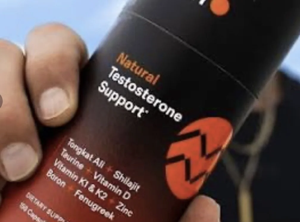 A close-up of a hand holding a bottle of a supplement labeled 'Natural Testosterone Support'.