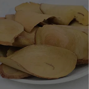 A close-up of thin, dried, yellowish-brown slices of a root piled on a white plate.