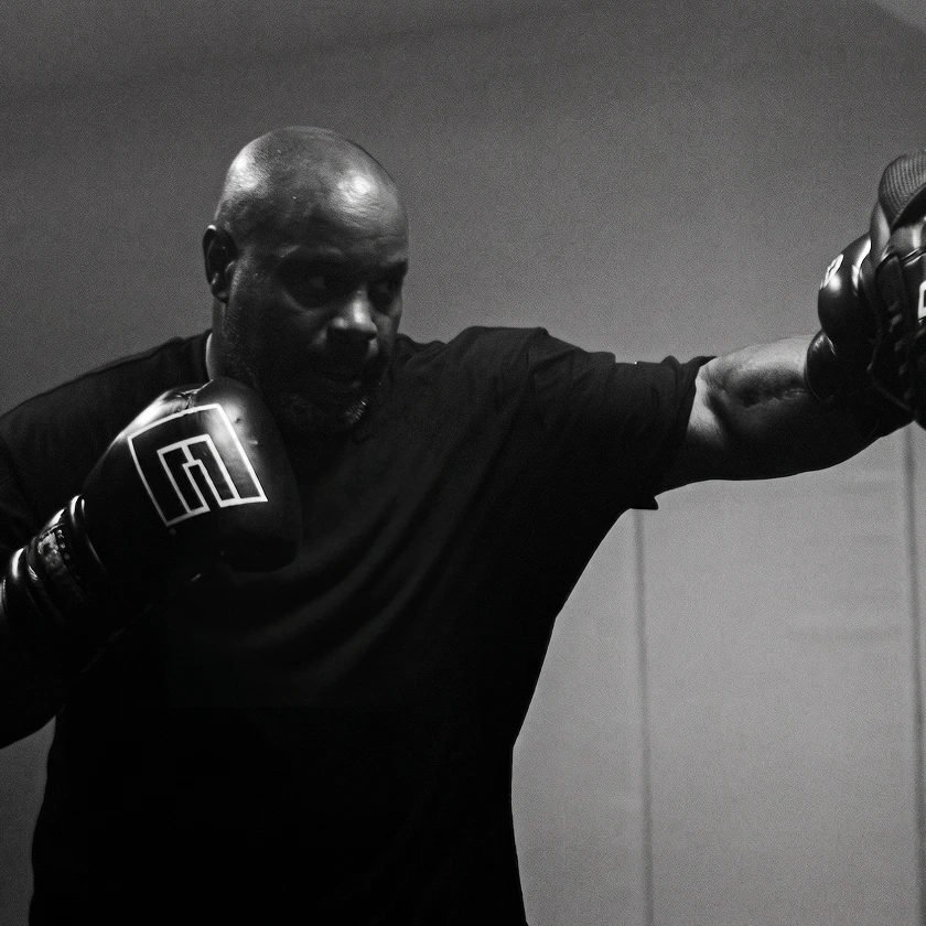 A black and white photo of a man in boxing gloves throwing a punch towards the right.