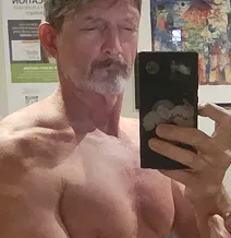 Man taking a shirtless mirror selfie with a phone.