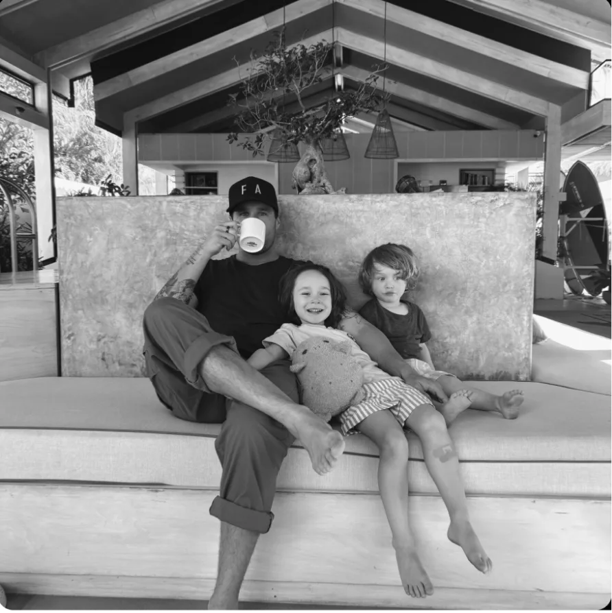 A black and white photo of a man sitting on a couch with two small children.