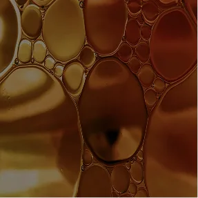 A close-up abstract image of oil bubbles in shades of gold and brown.